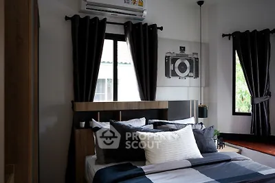 Cozy bedroom with modern decor, featuring a stylish bed, dark curtains, and a unique camera-themed wall art.