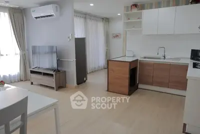Modern open-plan living room with kitchen, featuring sleek design and ample natural light.