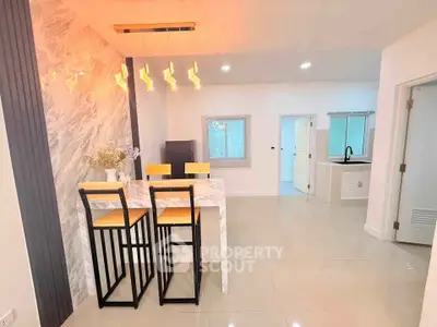 Modern open-plan kitchen and dining area with stylish lighting and marble accents.