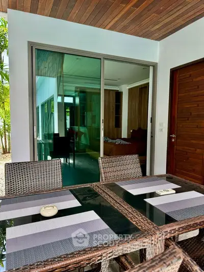 Stylish outdoor dining area with glass doors leading to modern interior
