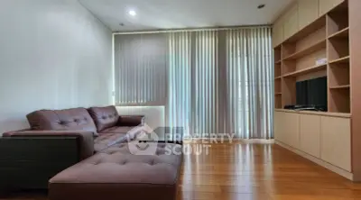 Spacious living room with modern furniture and natural light through vertical blinds.