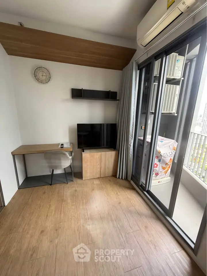 Modern living room with wooden flooring, desk, TV, and balcony access in stylish apartment.