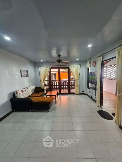 Spacious living room with large windows and balcony access, perfect for natural light and relaxation.