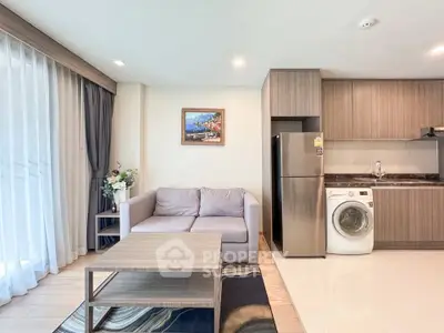 Modern living room with cozy sofa, stylish kitchen, and washing machine in open layout apartment.