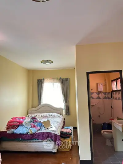 Cozy bedroom with attached bathroom, featuring natural light and simple decor.