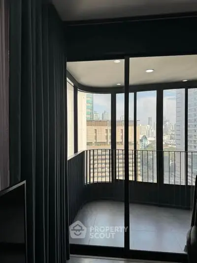 Modern apartment with floor-to-ceiling windows offering stunning city views from a cozy balcony.