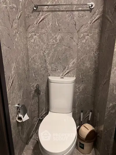 Modern bathroom with sleek marble tiles and contemporary toilet design.