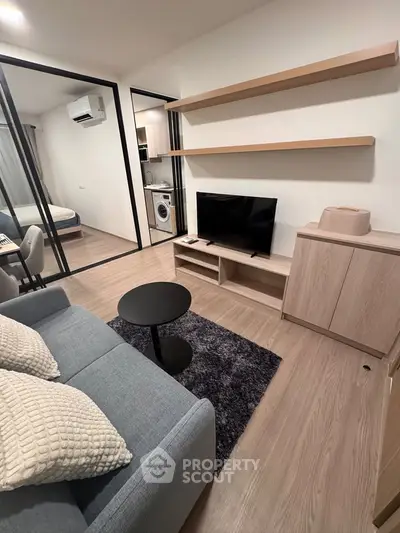Modern living room with sleek furniture and open layout, featuring a cozy sofa and wall-mounted shelves.