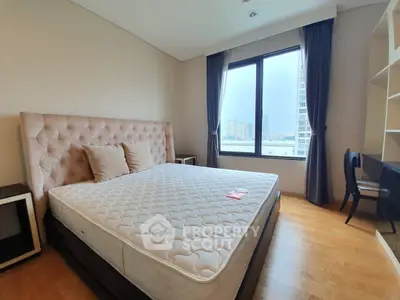 Spacious bedroom with large window and modern furnishings in a high-rise apartment.
