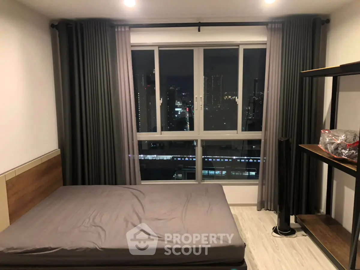Modern bedroom with city view, featuring sleek design and large window for natural light.