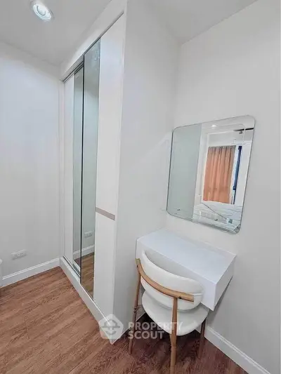 Modern bedroom with sleek vanity and mirrored closet in stylish apartment.