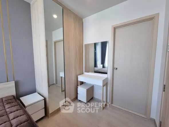 Modern bedroom with stylish furniture and mirrored wardrobe in a cozy apartment.