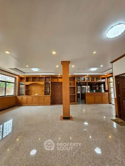 Spacious living room with elegant wooden built-in shelves and glossy tiled flooring.
