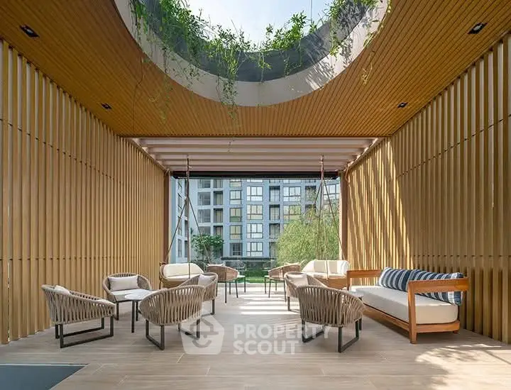 Modern outdoor seating area with stylish furniture and wooden slat ceiling, overlooking a contemporary building.