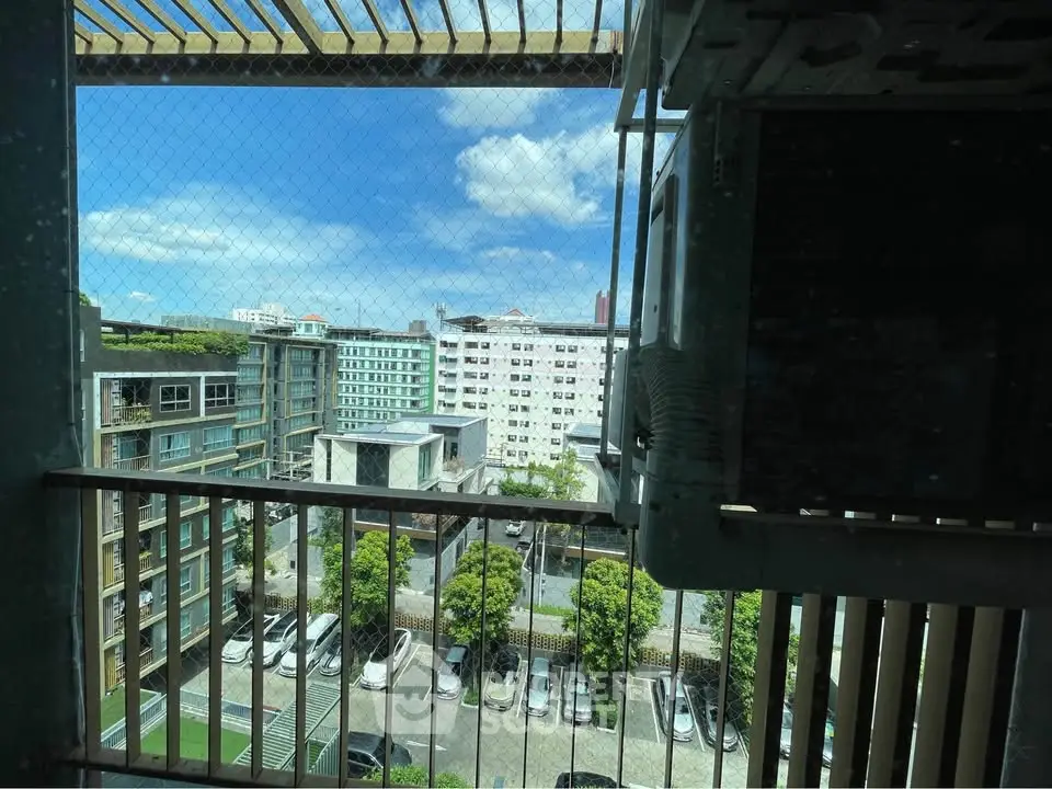 Scenic urban view from a balcony overlooking residential buildings and parking area.
