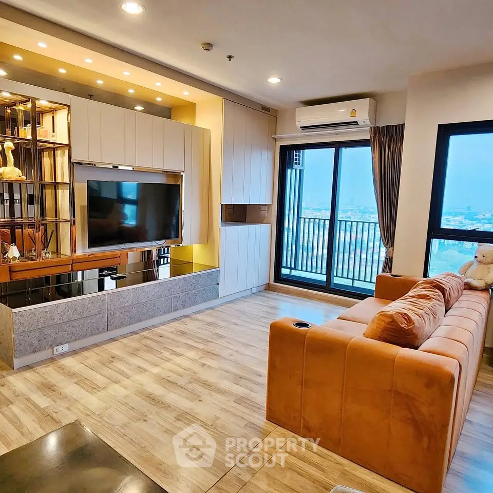 Modern living room with large TV, stylish shelving, and city view balcony.