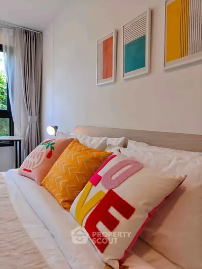 Cozy bedroom with colorful pillows and modern art, perfect for relaxation.
