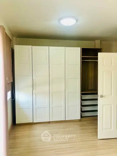 Spacious bedroom with modern wardrobe and wooden flooring