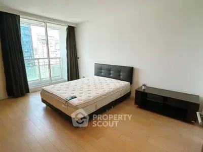 Spacious bedroom with large window and city view, featuring a modern bed and sleek wooden flooring.