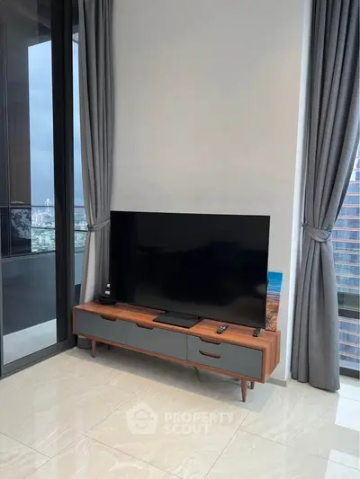 Modern living room with sleek TV stand and large window offering city views, perfect for urban living.