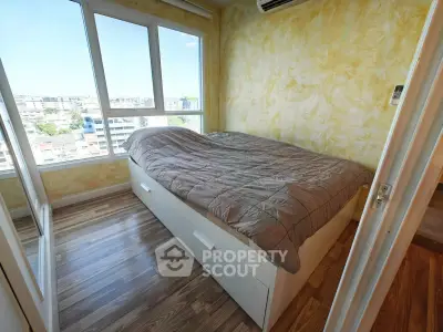 Cozy bedroom with large windows offering a stunning city view, featuring a comfortable bed and elegant wooden flooring.