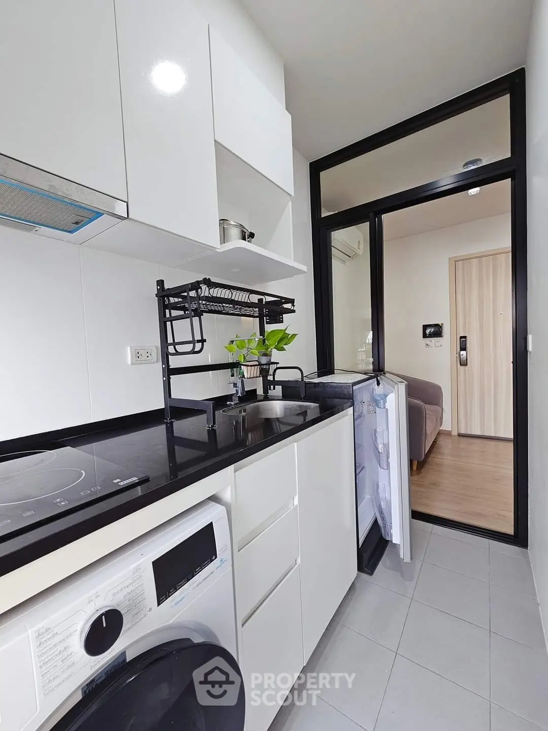 Modern kitchen with sleek appliances and open layout, featuring a washing machine and induction cooktop.
