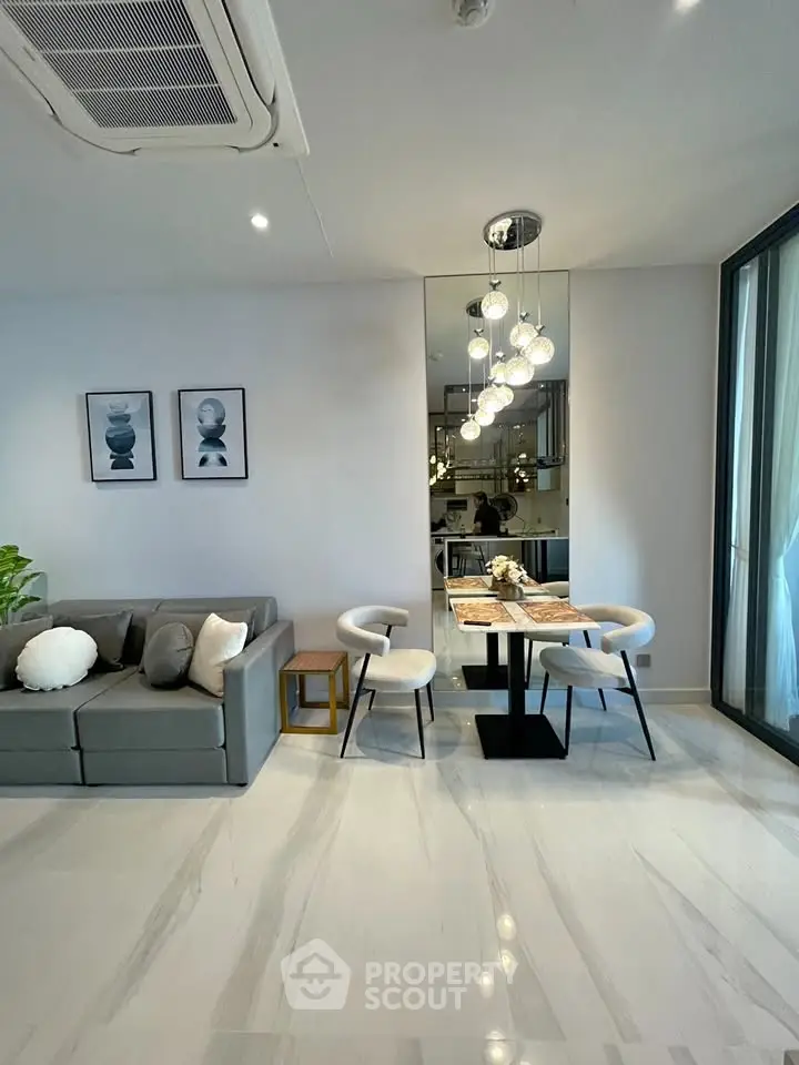 Modern living room with stylish decor and dining area, featuring elegant lighting and a cozy sofa.