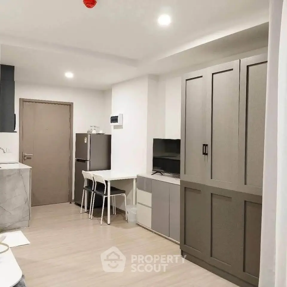 Modern apartment interior with sleek kitchen and cozy living area, featuring stylish cabinetry and compact design.