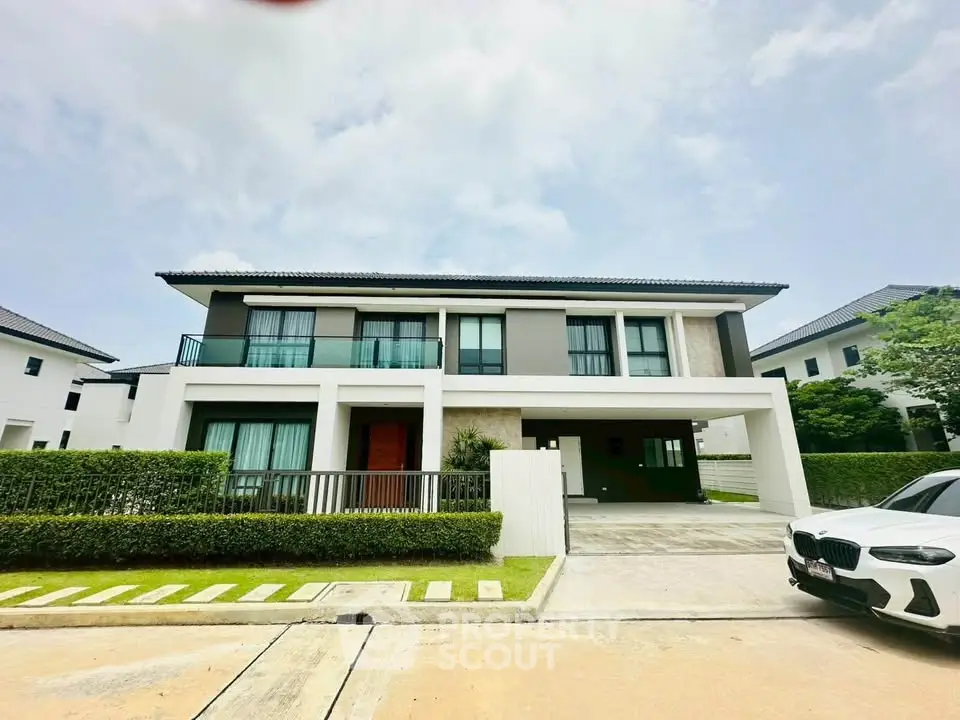Modern two-story house with sleek design and spacious driveway in a serene neighborhood.