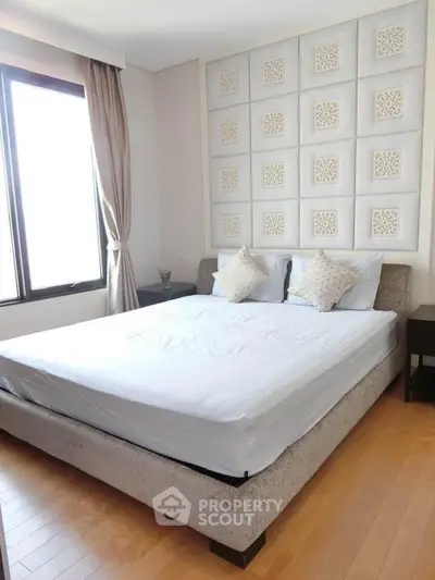 Spacious bedroom with elegant decor and large window for natural light.