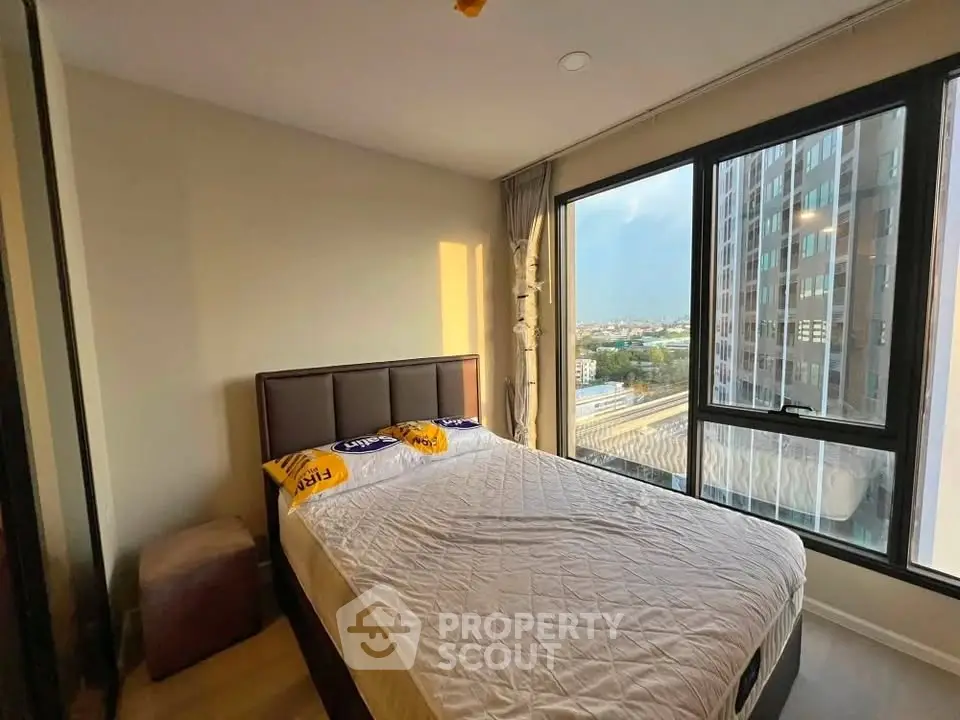 Modern bedroom with large windows offering city views in a high-rise apartment.