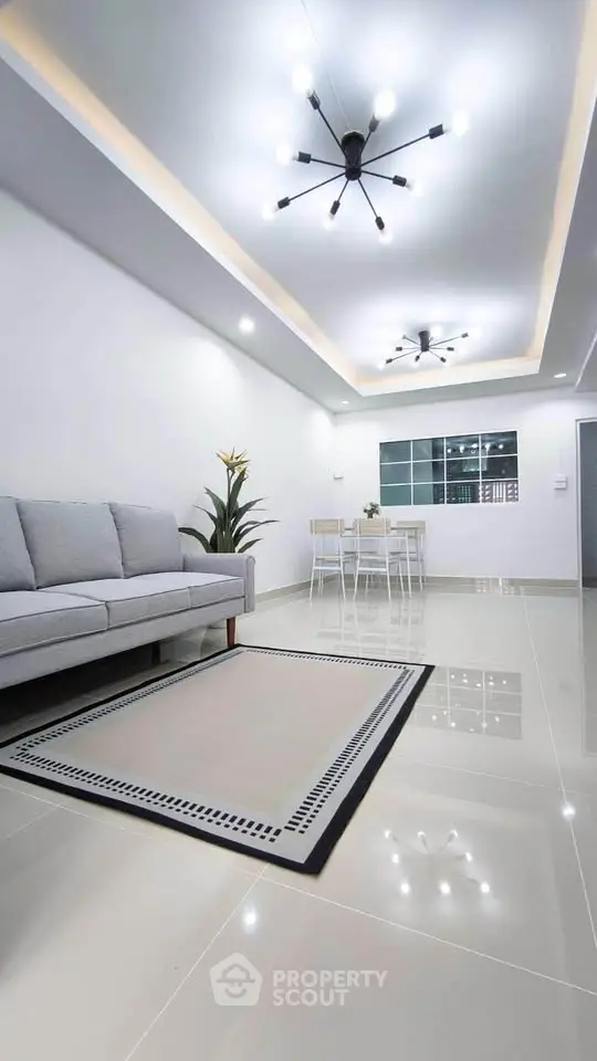 Modern living room with sleek lighting and elegant decor, featuring a cozy sofa and stylish dining area.