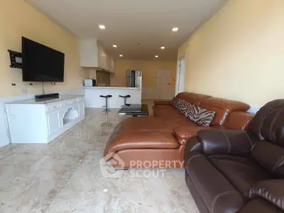 Spacious living room with modern leather sofa and open kitchen layout