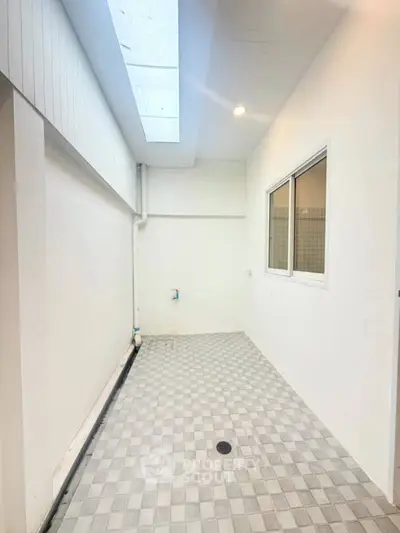 Bright utility area with skylight and tiled flooring, perfect for laundry or storage needs.