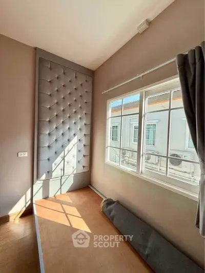 Cozy bedroom with tufted wall panel and large window for natural light