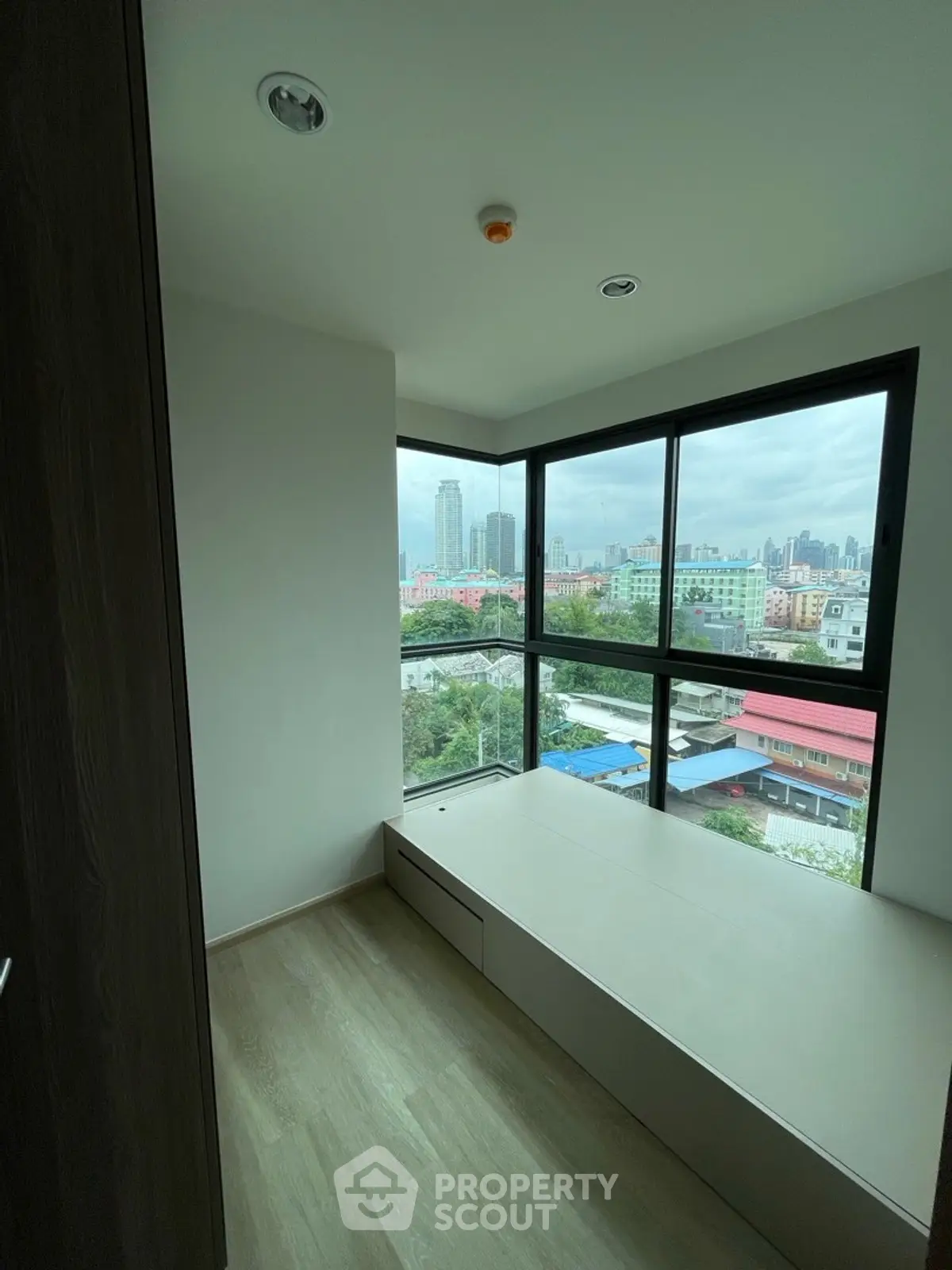 Modern bedroom with large windows offering stunning city views in a high-rise apartment.