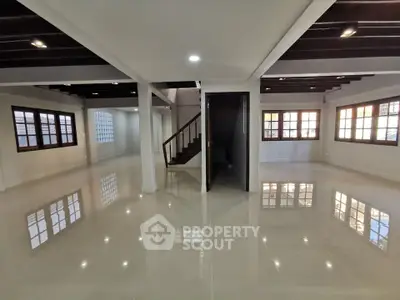 Spacious open-plan living area with glossy floors and modern staircase