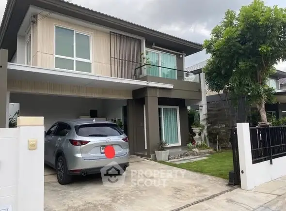 Modern two-story house with carport and landscaped garden in suburban setting.