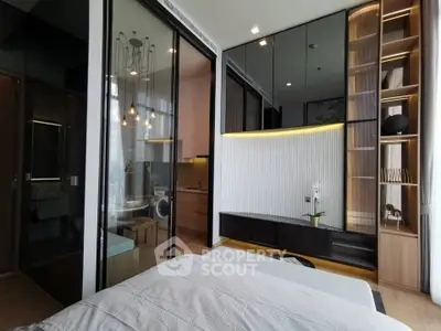 Modern bedroom with sleek design, glass partition, and integrated kitchen area in a stylish apartment.