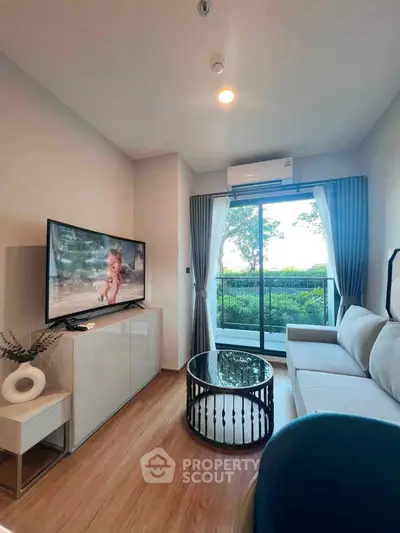 Modern living room with large TV, stylish furniture, and garden view through glass doors.