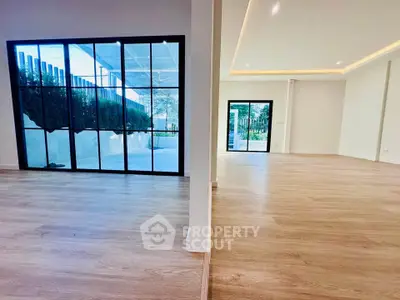 Spacious modern living room with large windows and wooden flooring, offering a seamless indoor-outdoor flow.