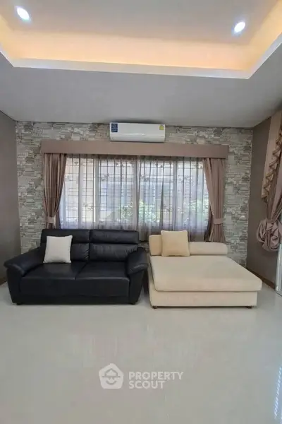 Spacious living room with modern sofas and large window, perfect for relaxation and entertaining.