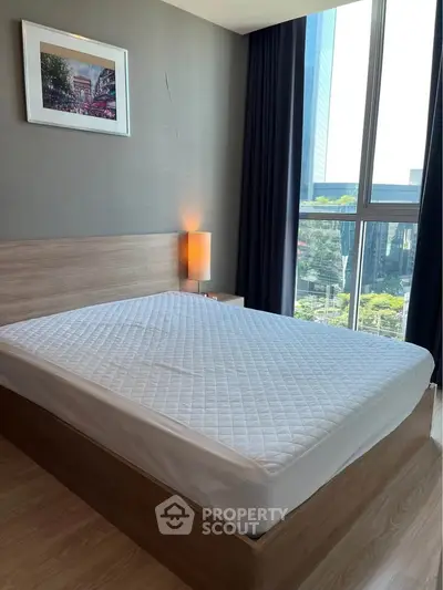 Modern bedroom with large window offering stunning city view, featuring a cozy bed and elegant decor.