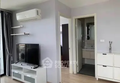 Modern living room with TV, air conditioning, and bathroom access in stylish apartment.
