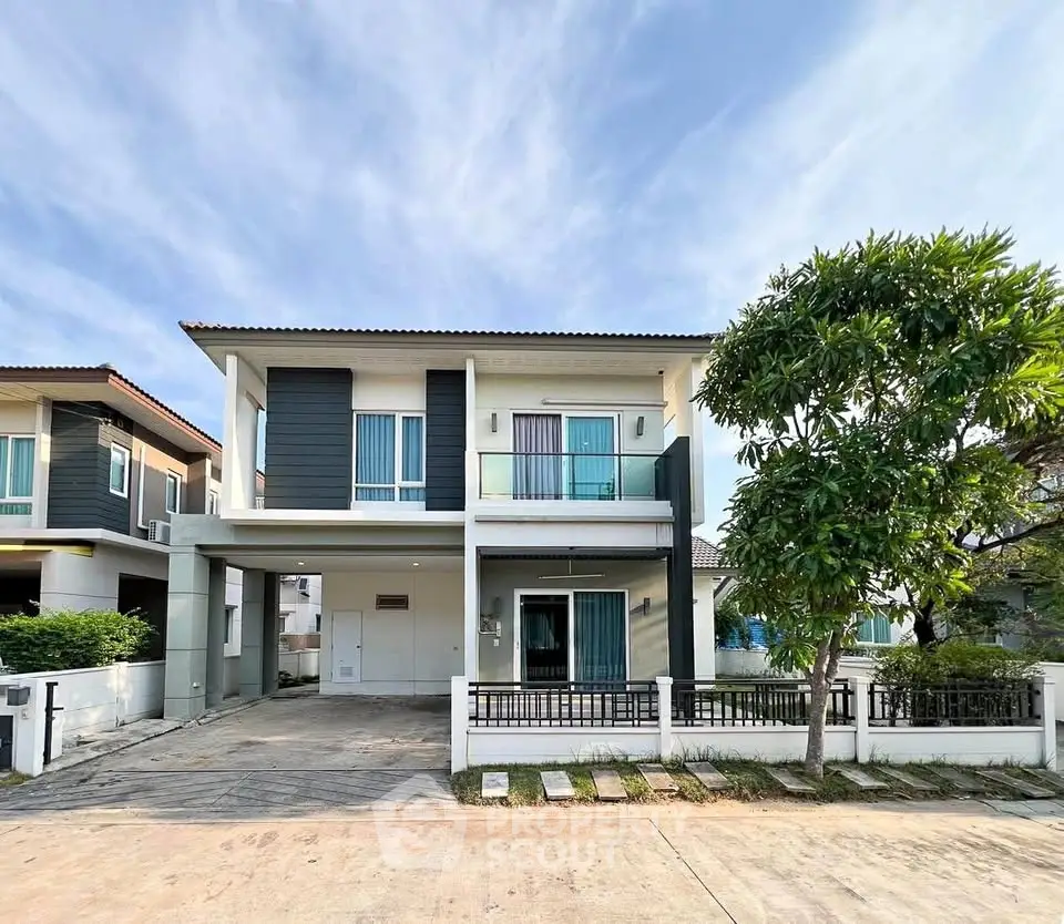 Modern two-story house with spacious driveway and lush greenery in a serene neighborhood.