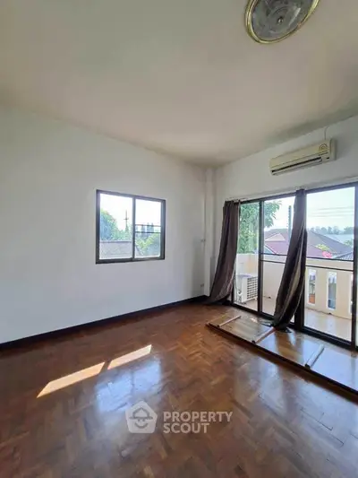 Spacious empty room with large windows and wooden flooring, perfect for customization.
