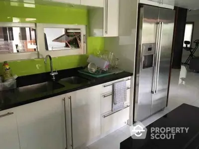 Modern kitchen with stainless steel fridge and vibrant green backsplash