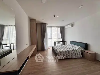 Spacious modern bedroom with large windows and stylish decor in a luxury apartment.