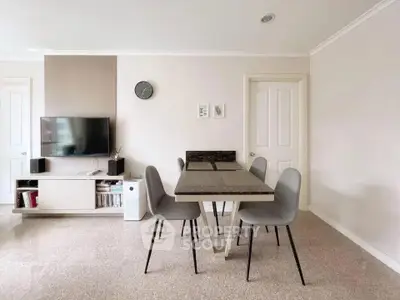 Modern dining area with sleek table and chairs, wall-mounted TV, and minimalist decor.