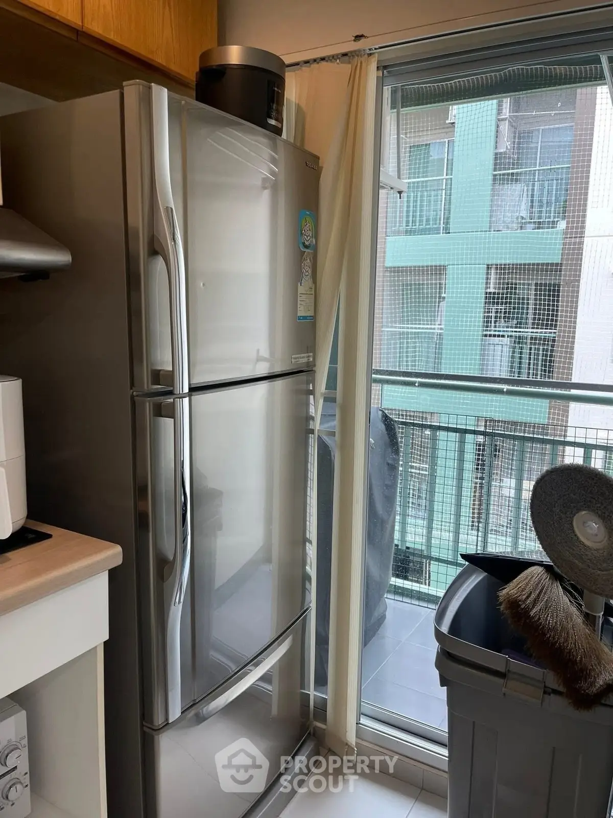 Modern kitchen with stainless steel fridge and balcony view in urban apartment